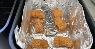 close up of scampi being cooked using foil in an air fryer basket