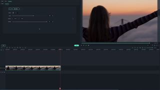Video of woman on beach at sunset with arms raised, being edited in Filmora interface