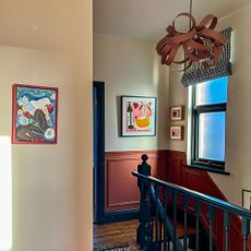 Landing area with painted panelling, statement pendant light and paintings on walls