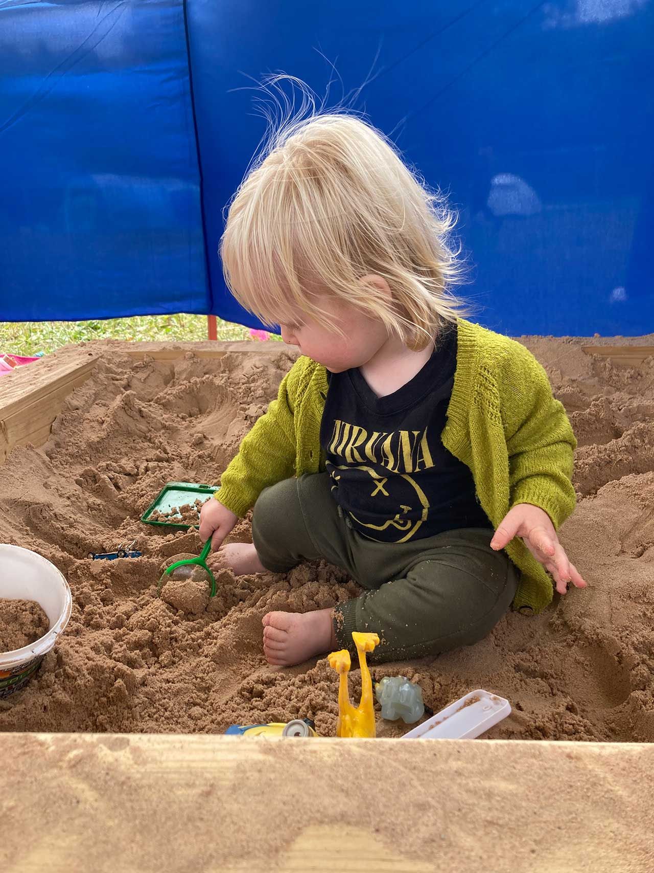 A young boy plays in a sandpit/play area in a festival camping area