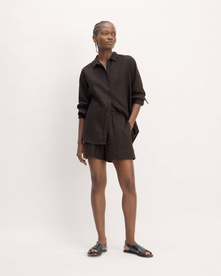 a model wears a black button-down shirt with matching short shorts