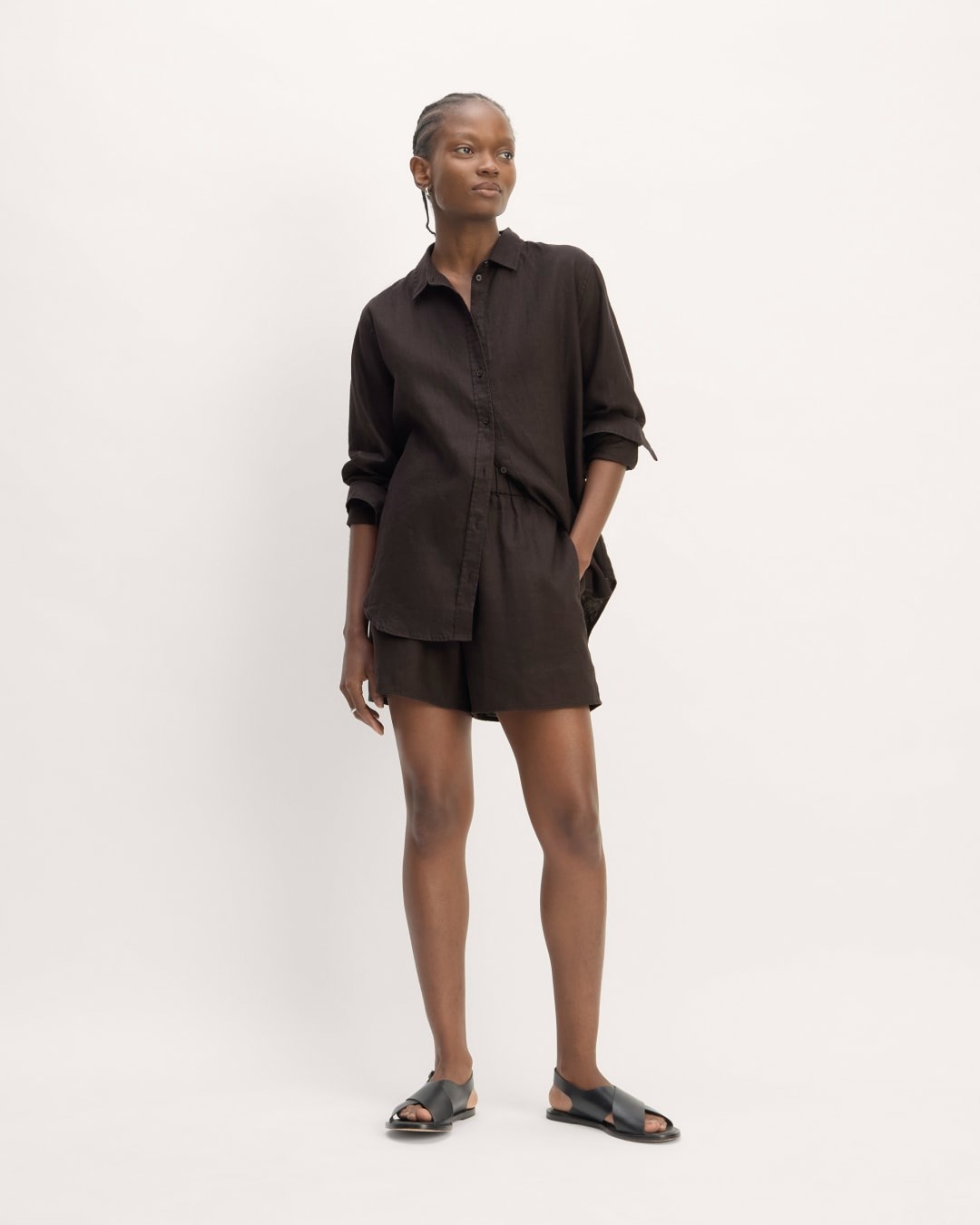 a model wears a black button-down shirt with matching short shorts