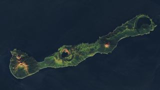 A satellite photo of a long thin island with four volcanoes equally space along its length
