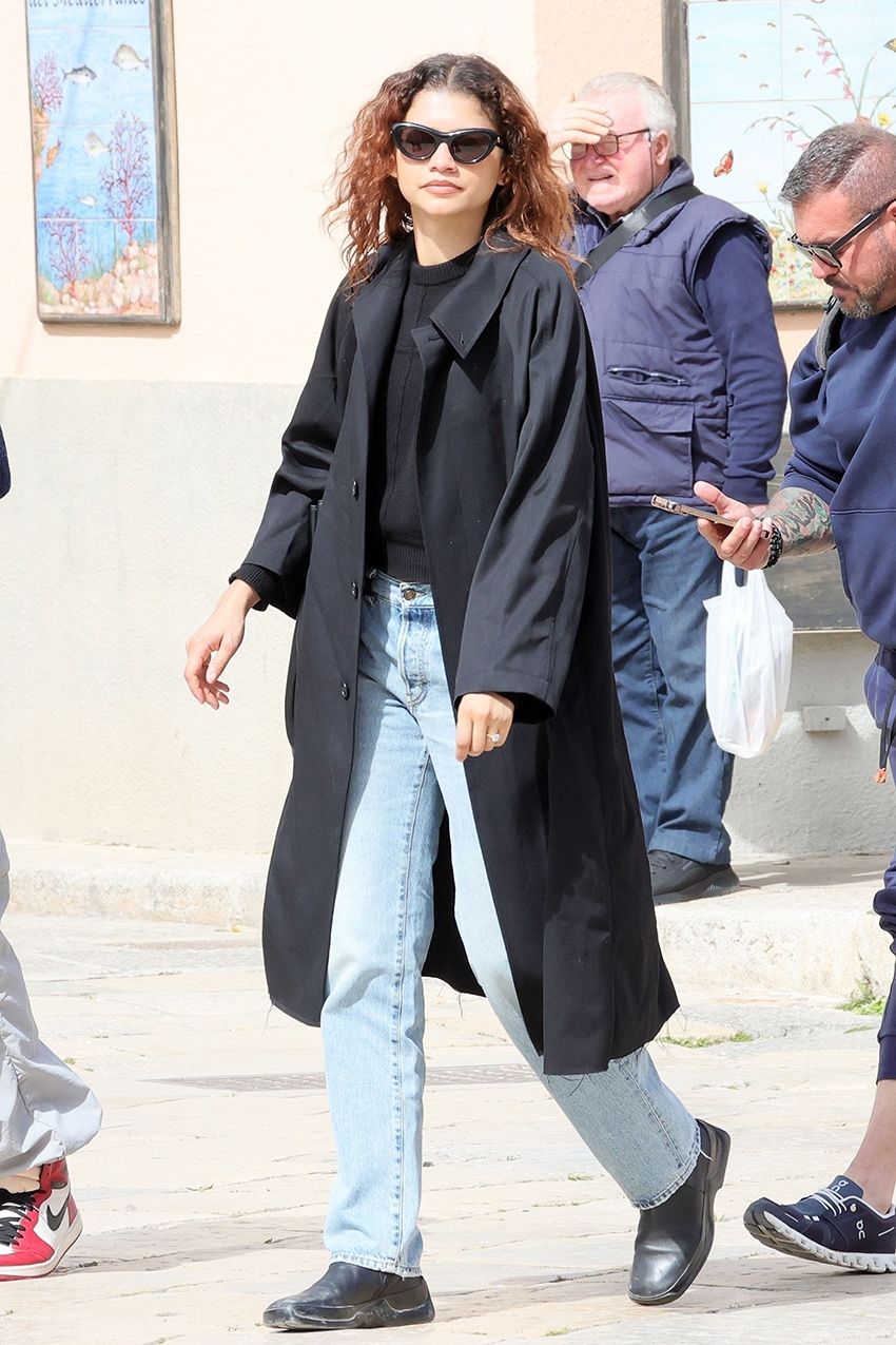 Zendaya wearing a black trench and light-wash jeans in Italy