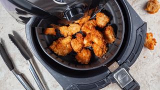 An air fryer with chicken nuggets laid out evenly across the basket