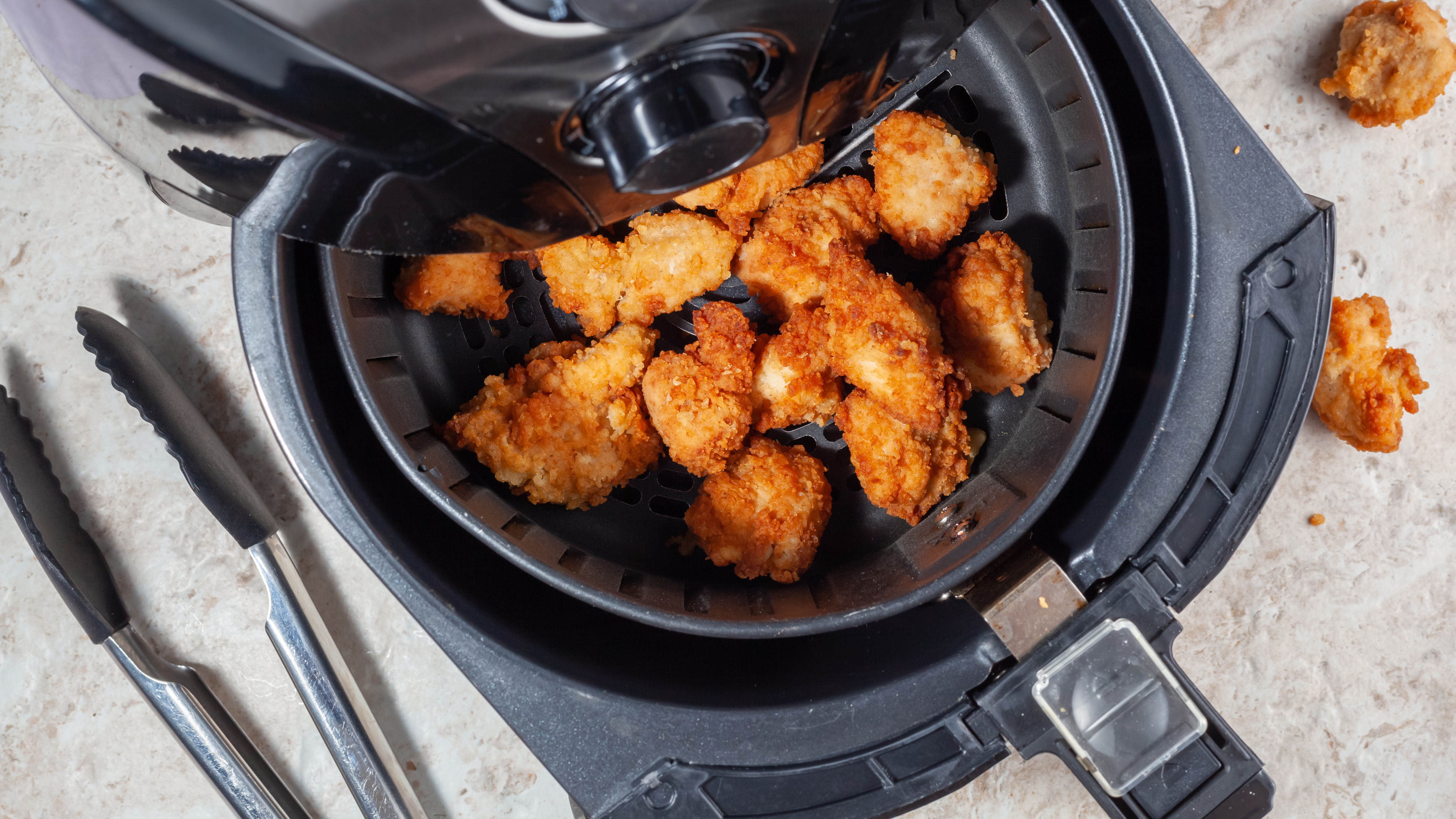 Uma fritadeira com nuggets de frango dispostos uniformemente na cesta