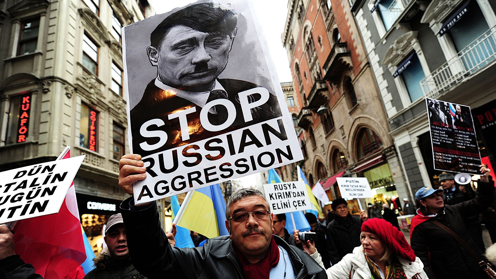 A placard reading 'Stop Russian aggression' and a picture of Vladimir Putin in the guise of Adolf Hitler is held at a protest in Turkey