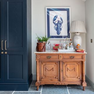 Corner of kitchen with marble topped wooden cabinet transformed into bar space with shakers, bottles and glassware