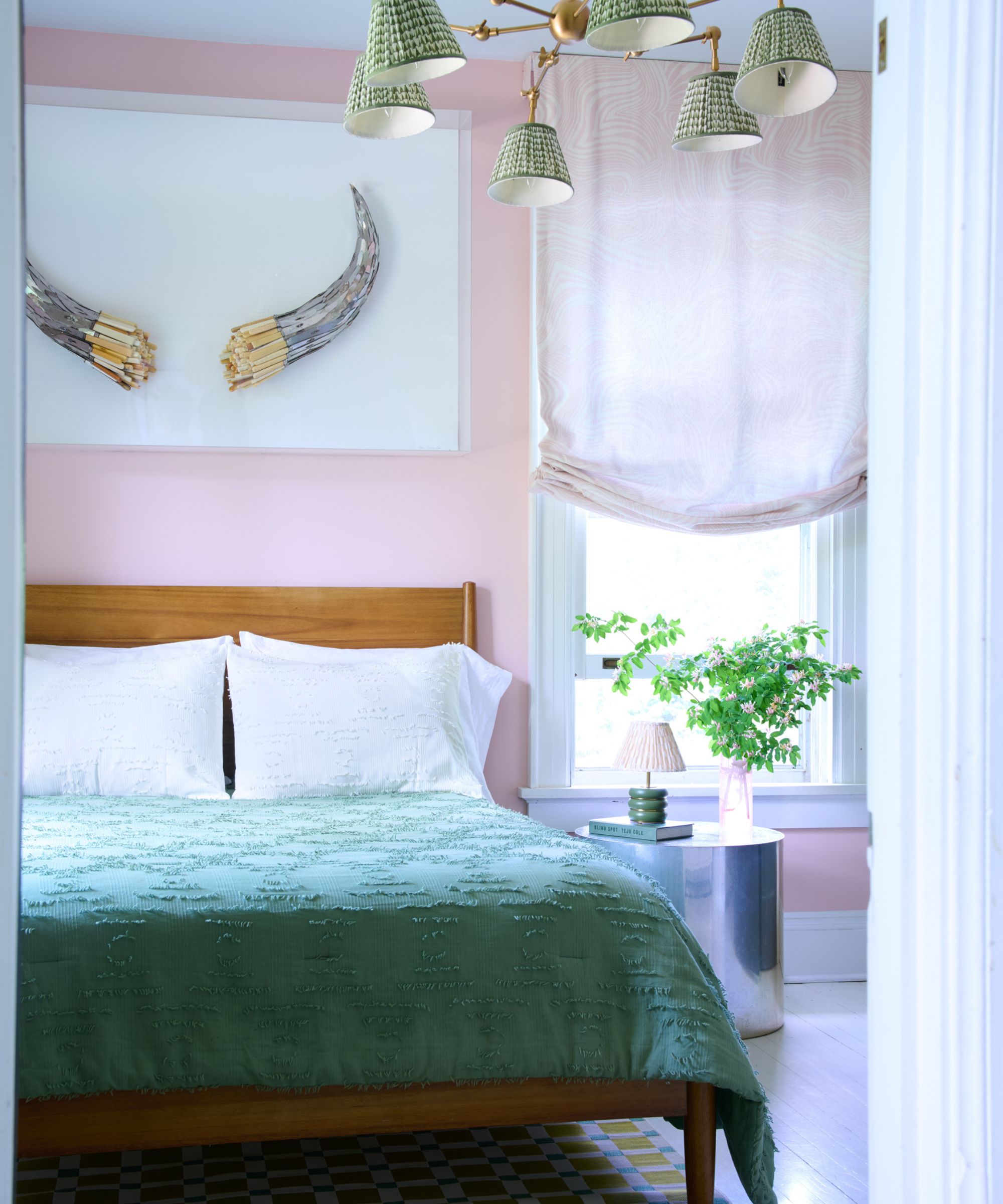pink bedroom with wooden bedframe and green bedding and silver round bedside table