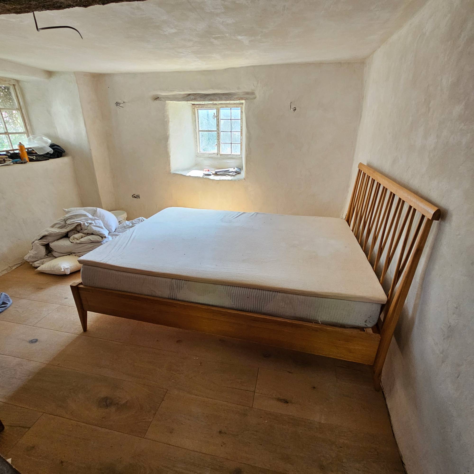 white lime plastered bedroom with wooden floor and bed