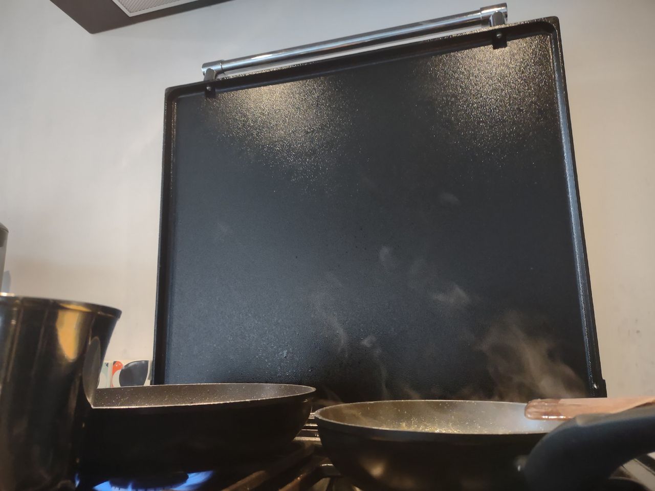 Steam rising from frying pans on a hob