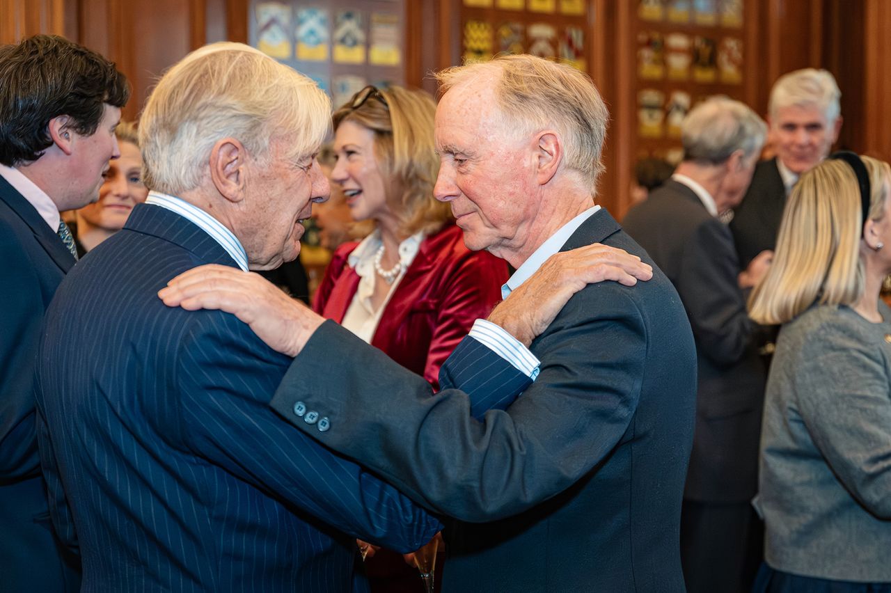 Photograph of two older gentlemen with a hand on each other's shoulder, reuniting from an old friendship. Taken at the Georgian Group Architecture Awards night in London, UK, by Marc James.