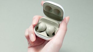 a hand holding the samsung galaxy buds 2 in olive