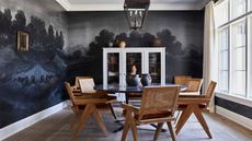 image of a dining room with a navy nature scene wall mural and a modern round table with scandi wooden chairs in the center of the room