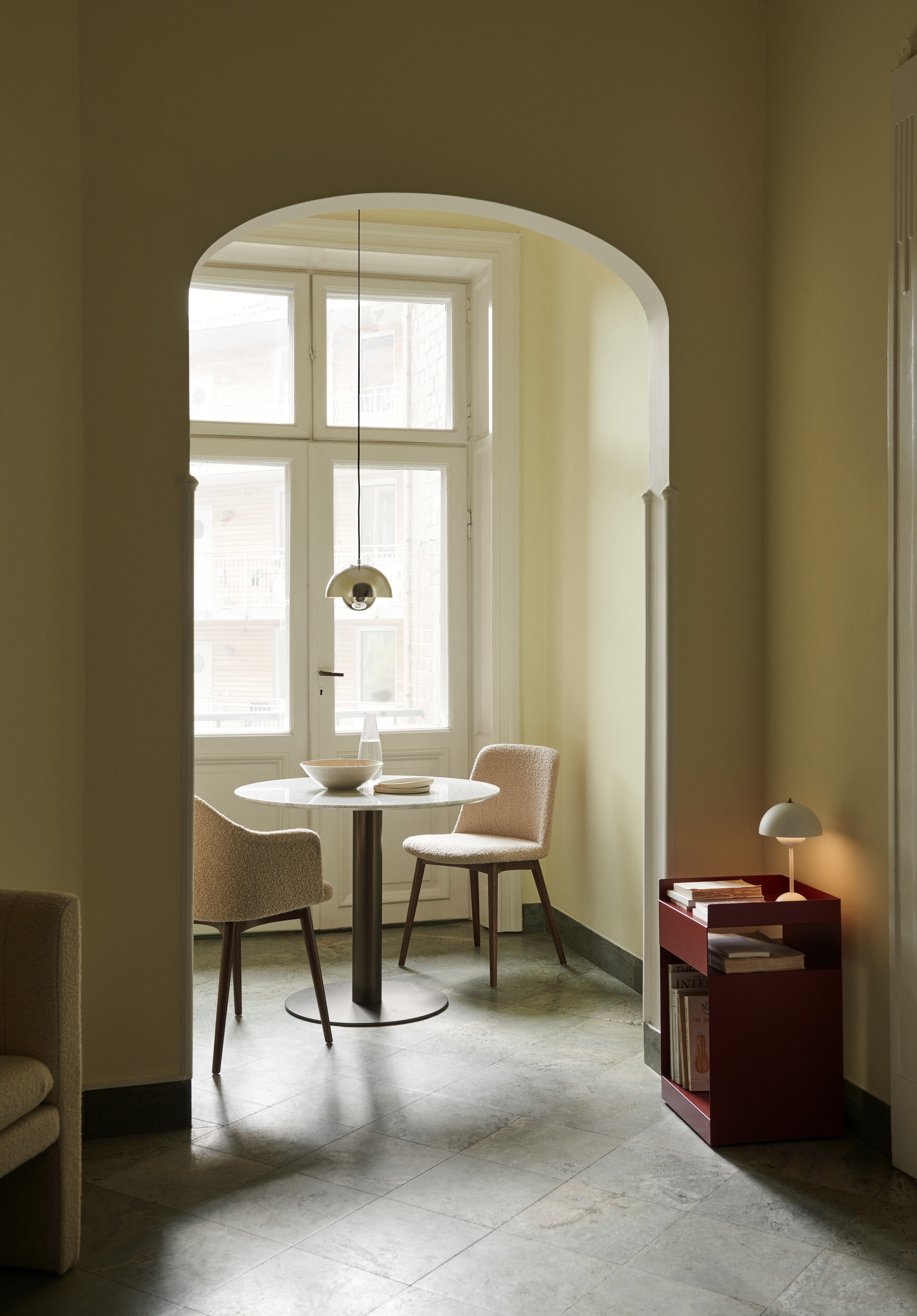 a yellow painted dining nook with a small table with pink chairs