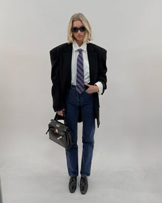 Elsa Hosk wearing a blazer, shirt, and tie with jeans for a Helsa campaign.