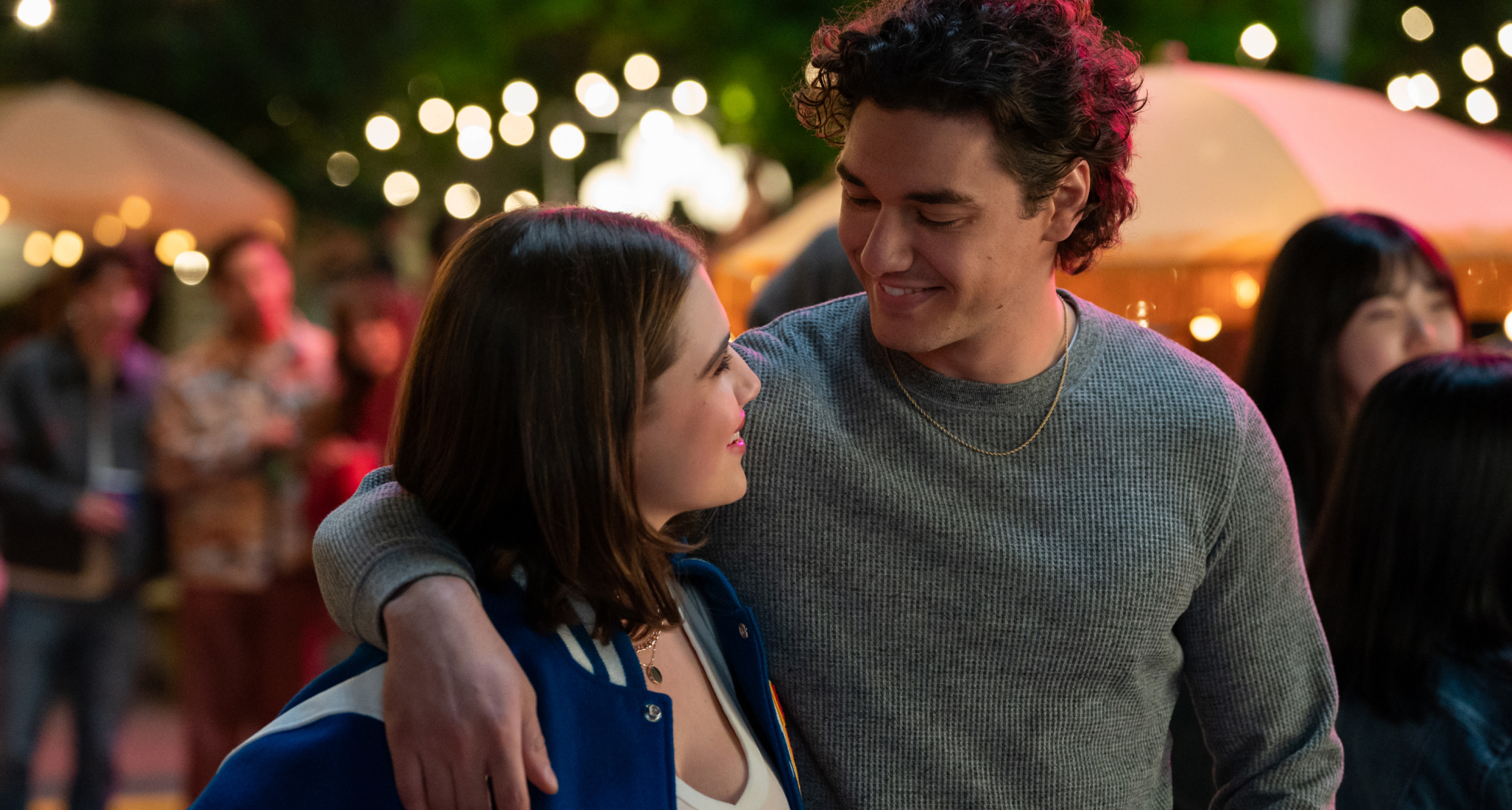 Hannah (Ella Bright) and Garrett (Belmont Cameli) walk with his arm over her shoulder through an on campus event in off campus season 1