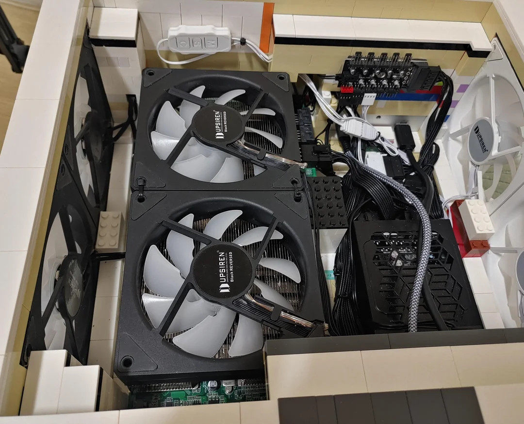 Close-up of a custom PC built inside a LEGO case, featuring visible cooling fans, cables, and computer components creatively assembled.