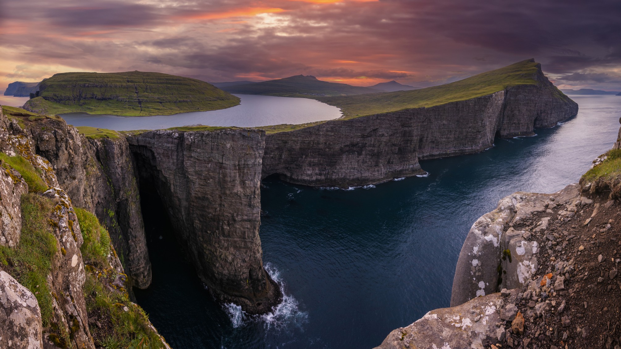 View of the largest lake in the Faroe Islands where it appears to hang over the Atlantic Ocean.