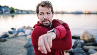 Man stretching on beach wearing sports watch