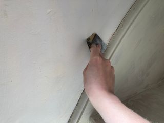 Sanding around the wall string of a staircase before caulking
