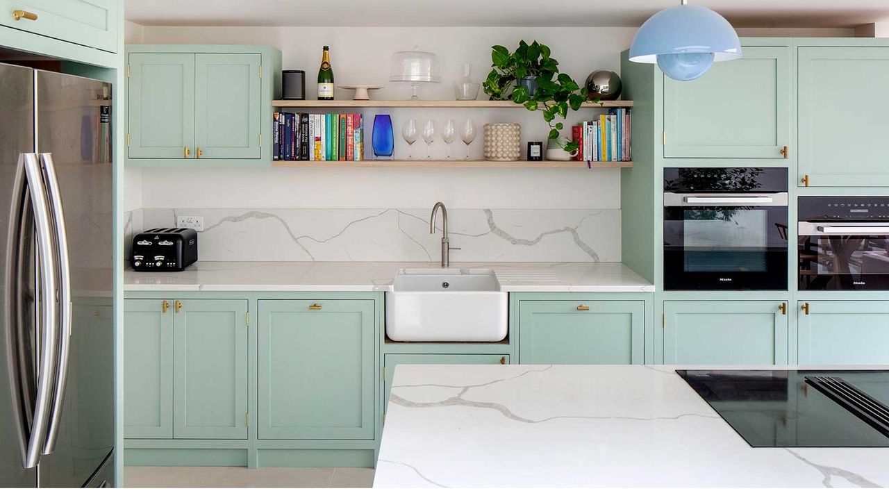 mint green Shaker kitchen with marble topped kitchen island and Belfast sink and open shelving to show the kitchen triangle design