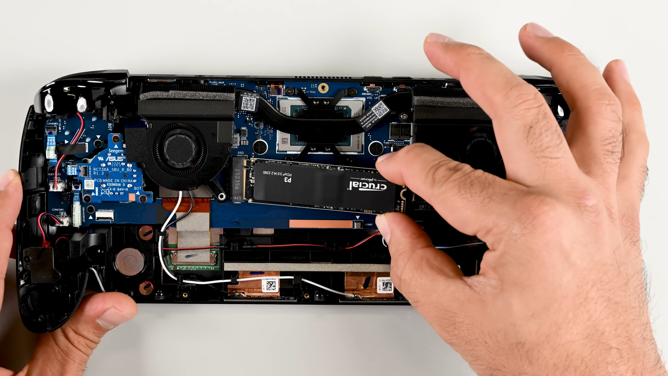 iFixit showing inside a disassembled Asus ROG Xbox Ally X, upgrading the M.2 SSD to a Crucial one