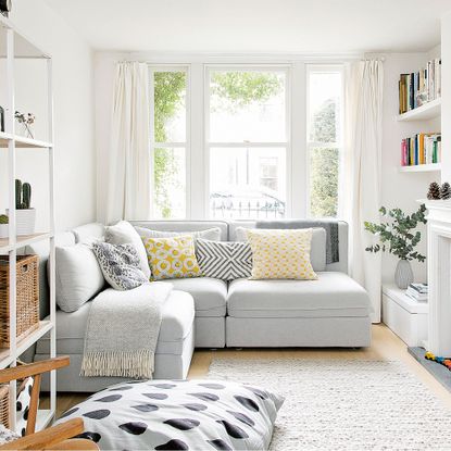 small white living room with corner sofa and shelving unit plus rug
