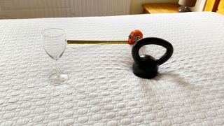 A wine glass, a weight and a tape measure on a Simba GO Hybrid mattress