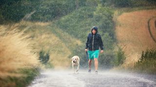 Dog owner and dog walking in the rain