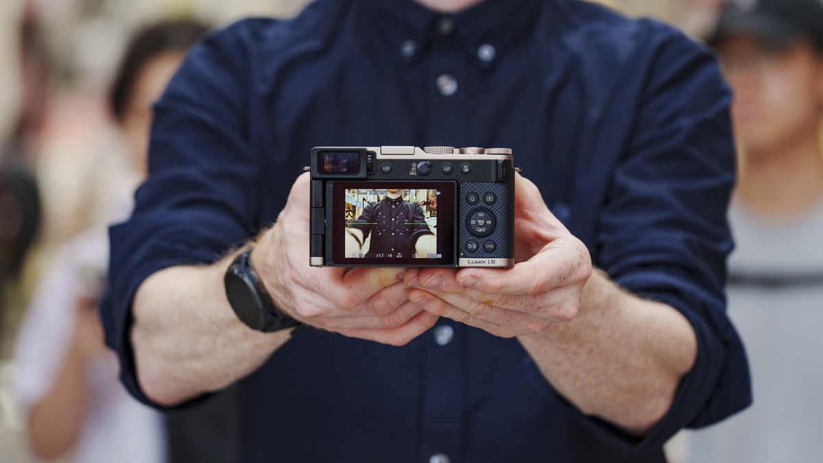Man holding the Panasonic Lumix L10 compact camera in an urban setting of Japan