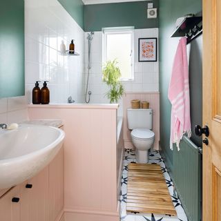 green bathroom with white square tiles, pink wooden panelling, white suite, black and white star floor tiles