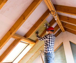 man wearing checked shirt adding roof insulation