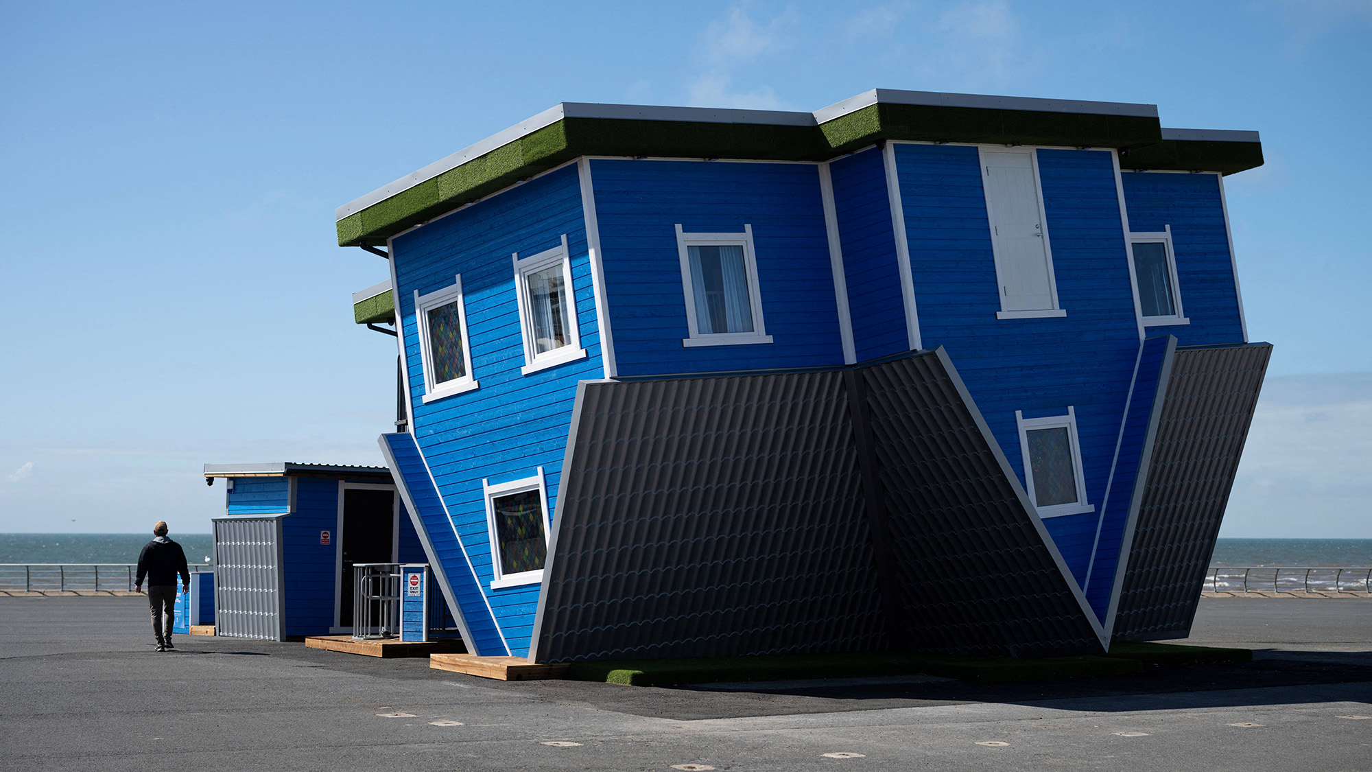 A man walks past the 'Upside Down House', an attraction located on the Promenade in Blackpool, England