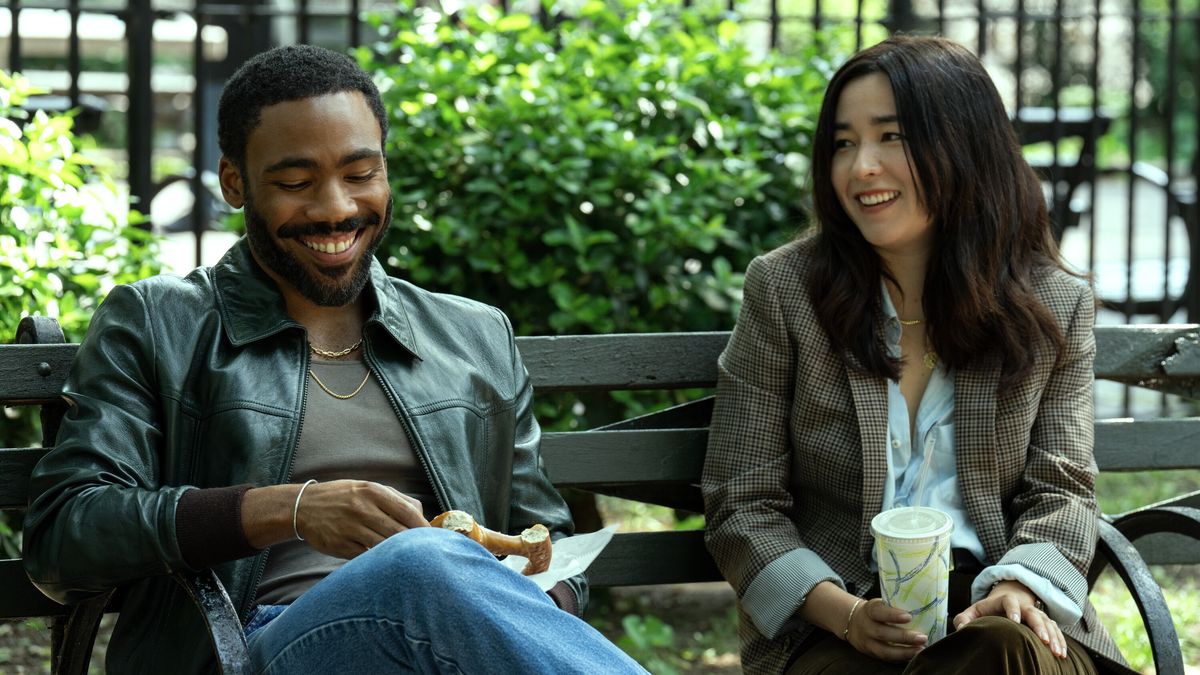 John (Donald Glover) and Jane (Maya Erskine) sitting on a park bench together, smiling, in Mr. &amp; Mrs. Smith episode 1