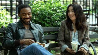 John (Donald Glover) and Jane (Maya Erskine) sitting on a park bench together, smiling, in Mr. & Mrs. Smith episode 1