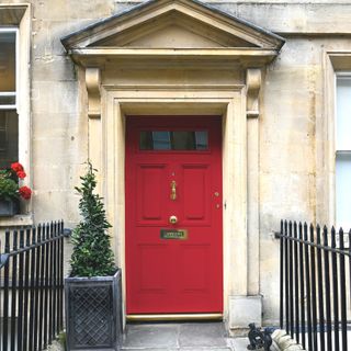 front door painted in red with stone facade