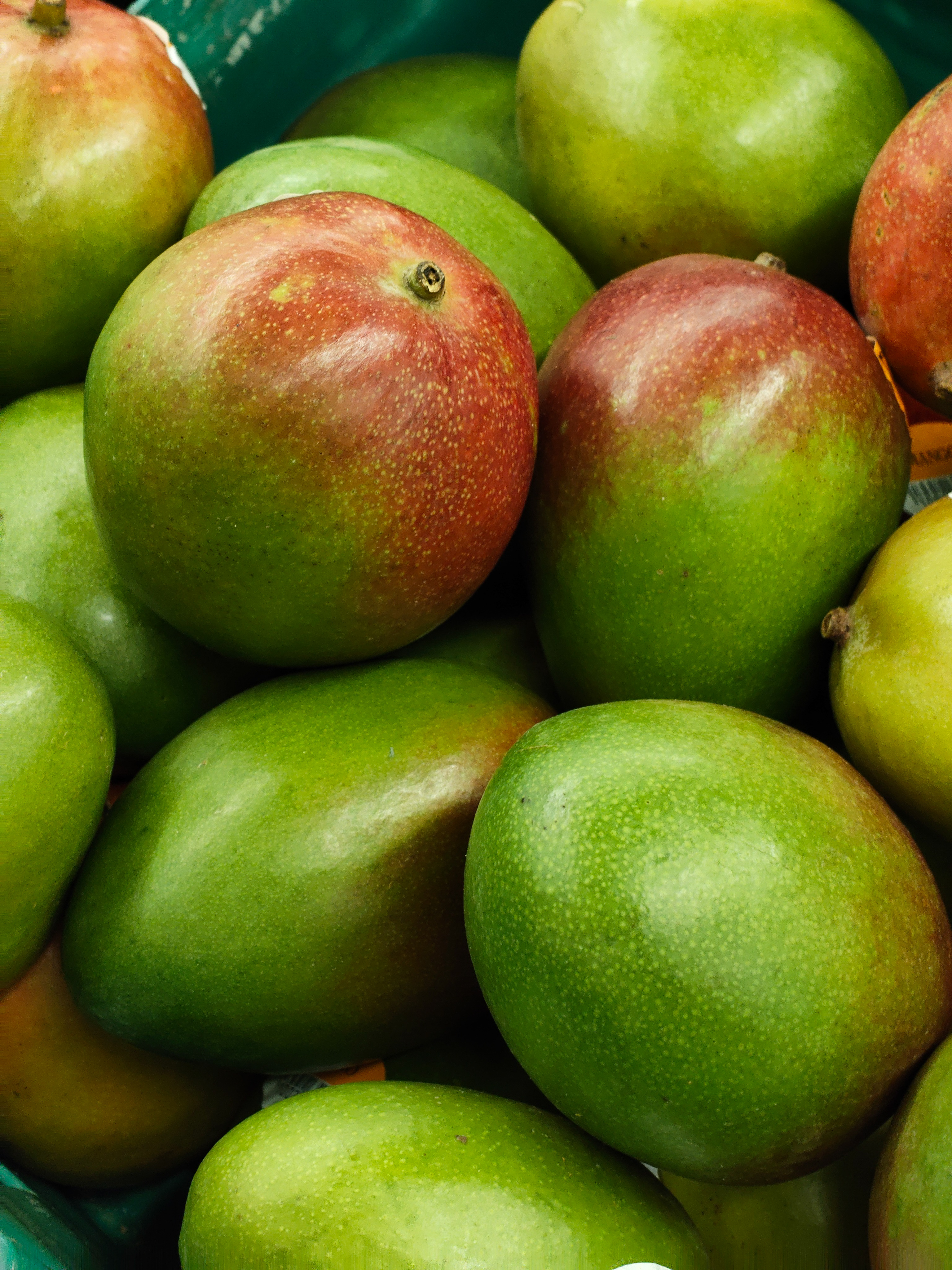 Pile of ripe green and red mangoes stacked in a market display, photographed with the Nothing Phone (4a).