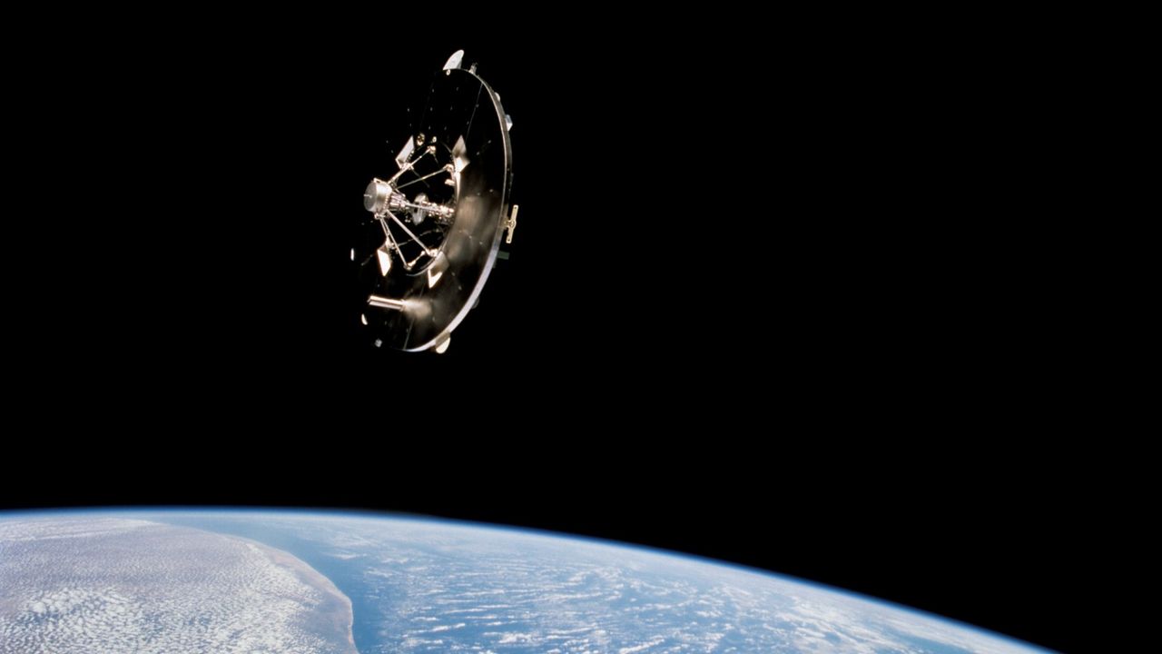 A disk-shaped science experiment called the Wake Shield Facility flies over Earth on STS-69 in September 1995.