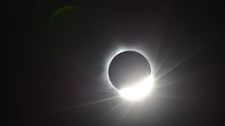 The moon covering the sun, with a "diamond ring" half circle of light toward the lower right corner.