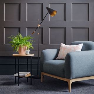 blue single sofa with decorative table, lamp, and grey wall panelling