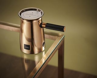A copper Hotel Chocolat velvetiser machine on brass-edged glass coffee table