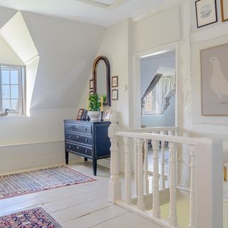 room with attic ceiling and white wall and wooden floor and blue chest with drawers and white railing