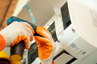 Hands wearing safety gloves installing a new HVAC system.