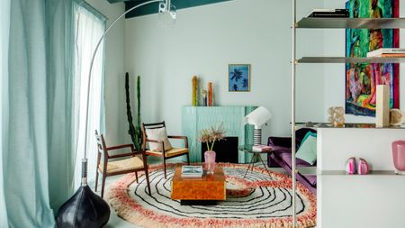 Living room with turquoise ceiling, turquoise tiled fireplace, circular rug and wooden armchairs with burl wood coffee table