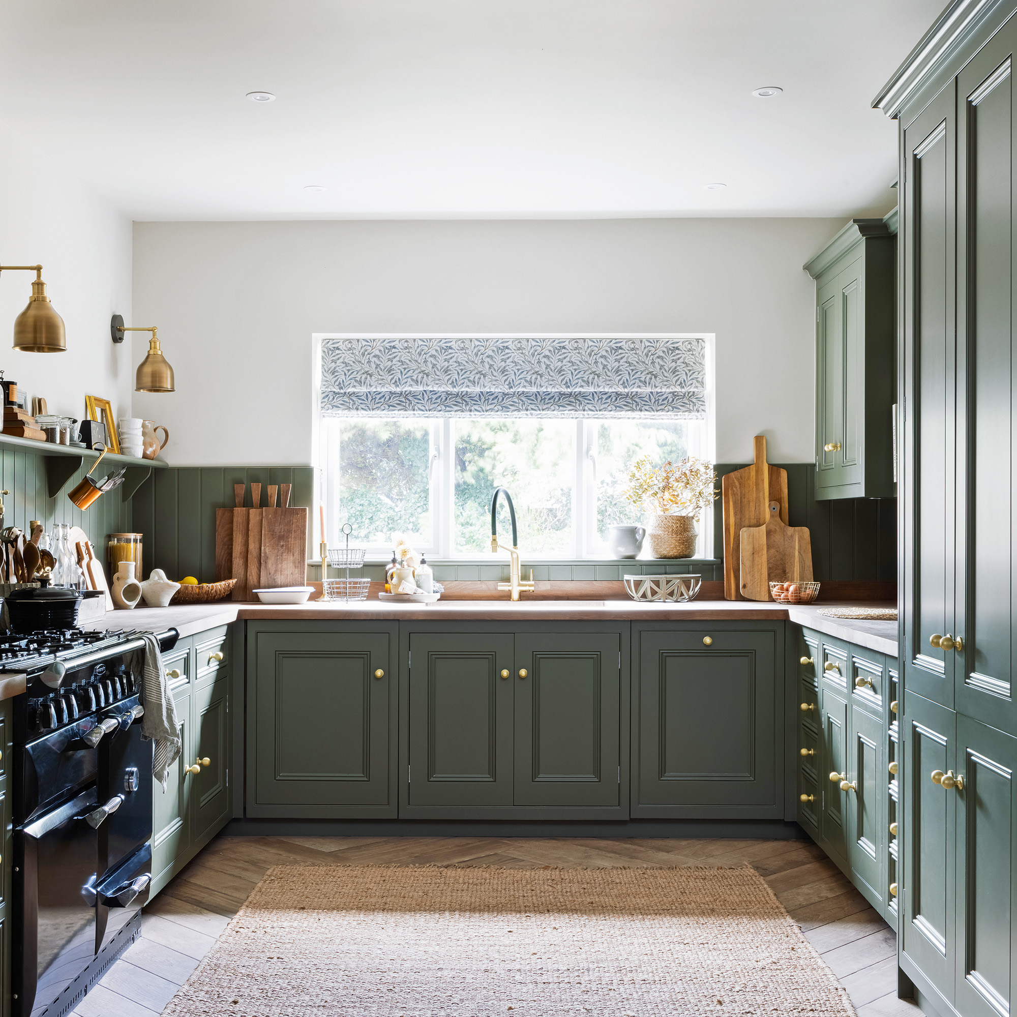 green secondhand kitchen with brass handles with black range cooker dresser and window with sink area