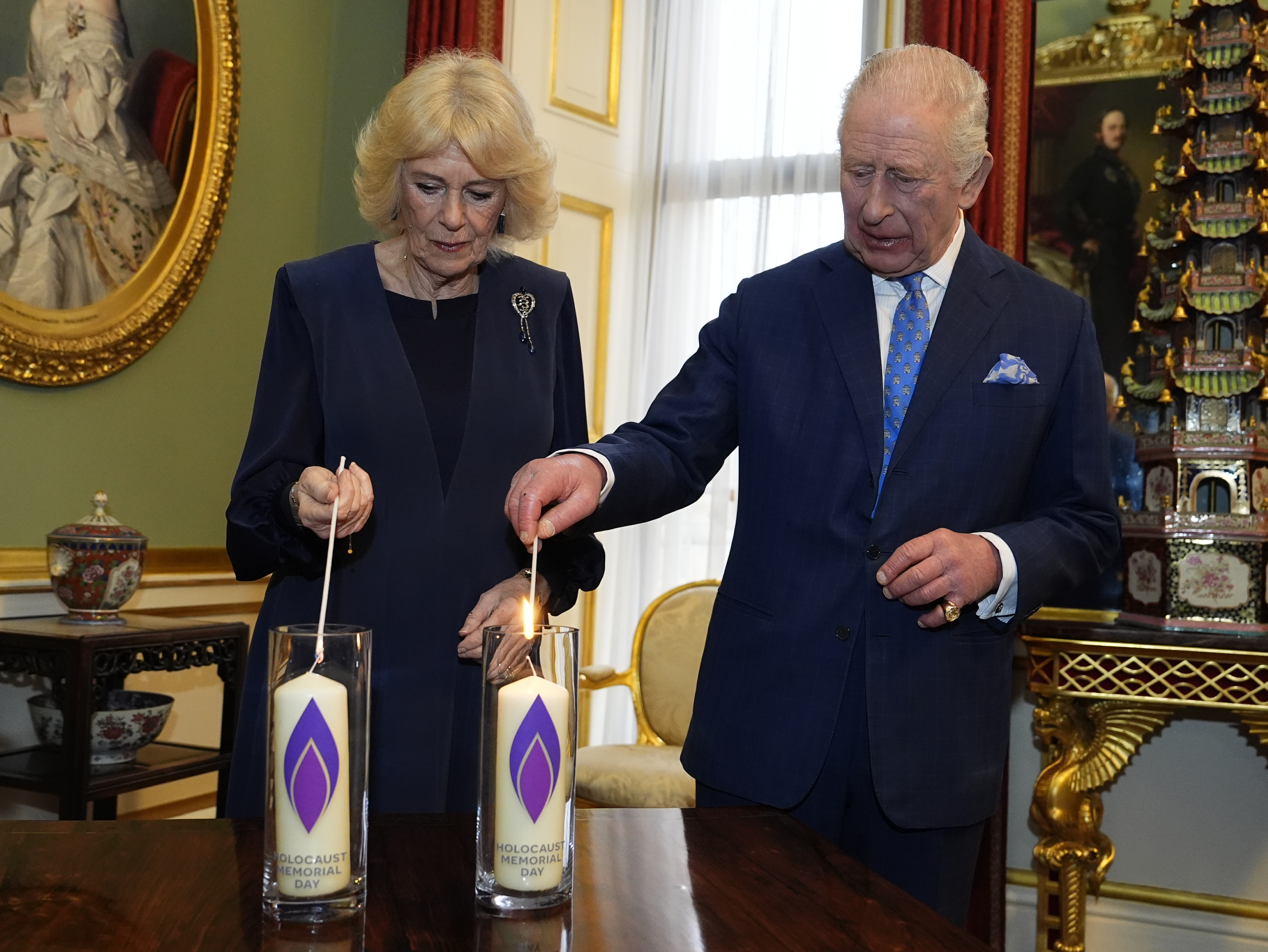 Queen Camilla and King Charles lighting candles on a table for Holocaust Memorial Day