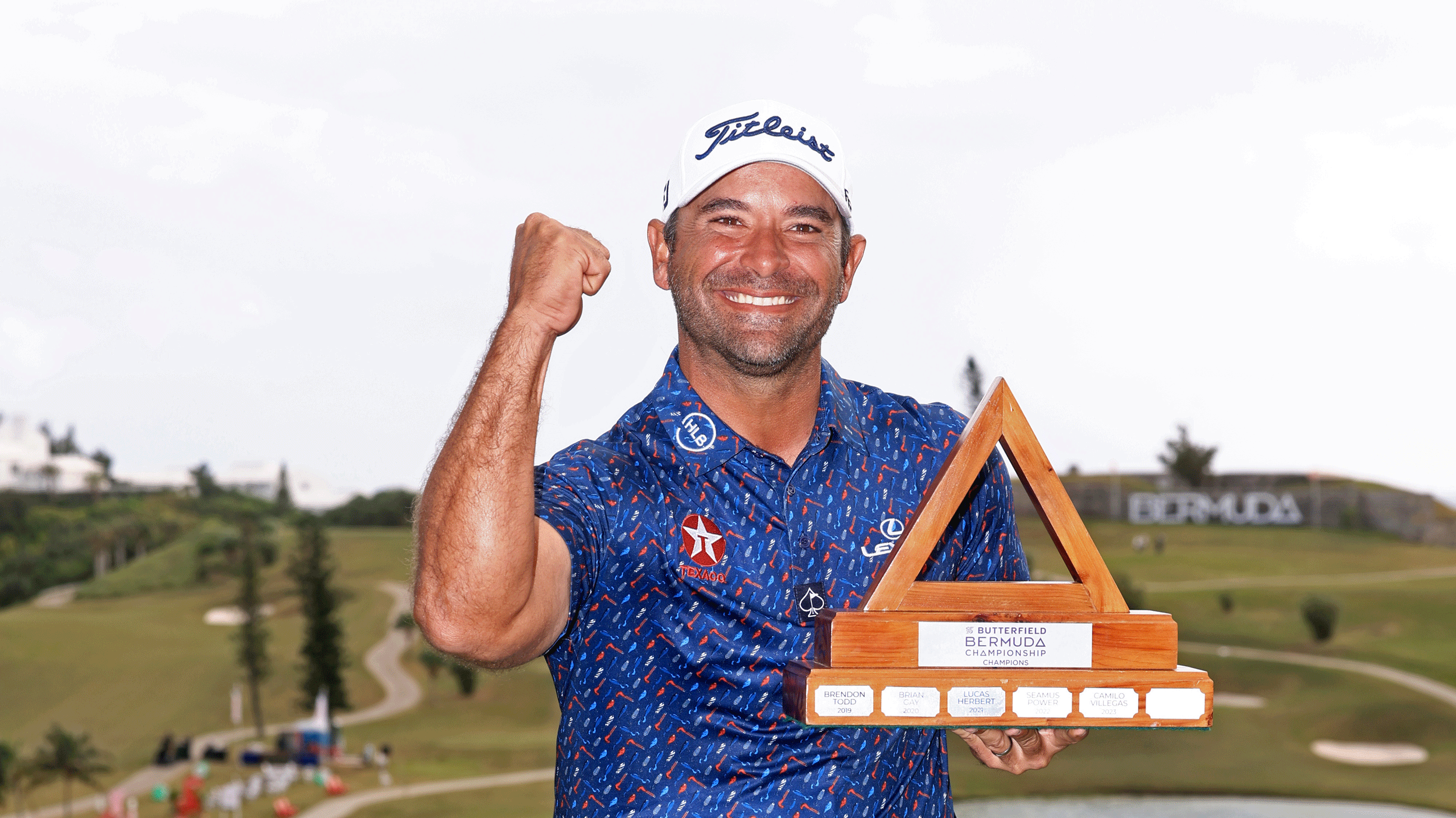 Rafael Campos punches the air while holding the Butterfield Bermuda Championship trophy in 2024
