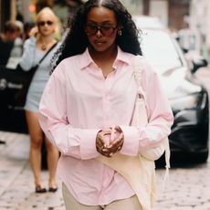 A Copenhagen Fashion Week attendee wearing a pink button-down shirt. 