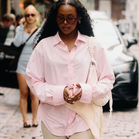 A Copenhagen Fashion Week attendee wearing a pink button-down shirt. 